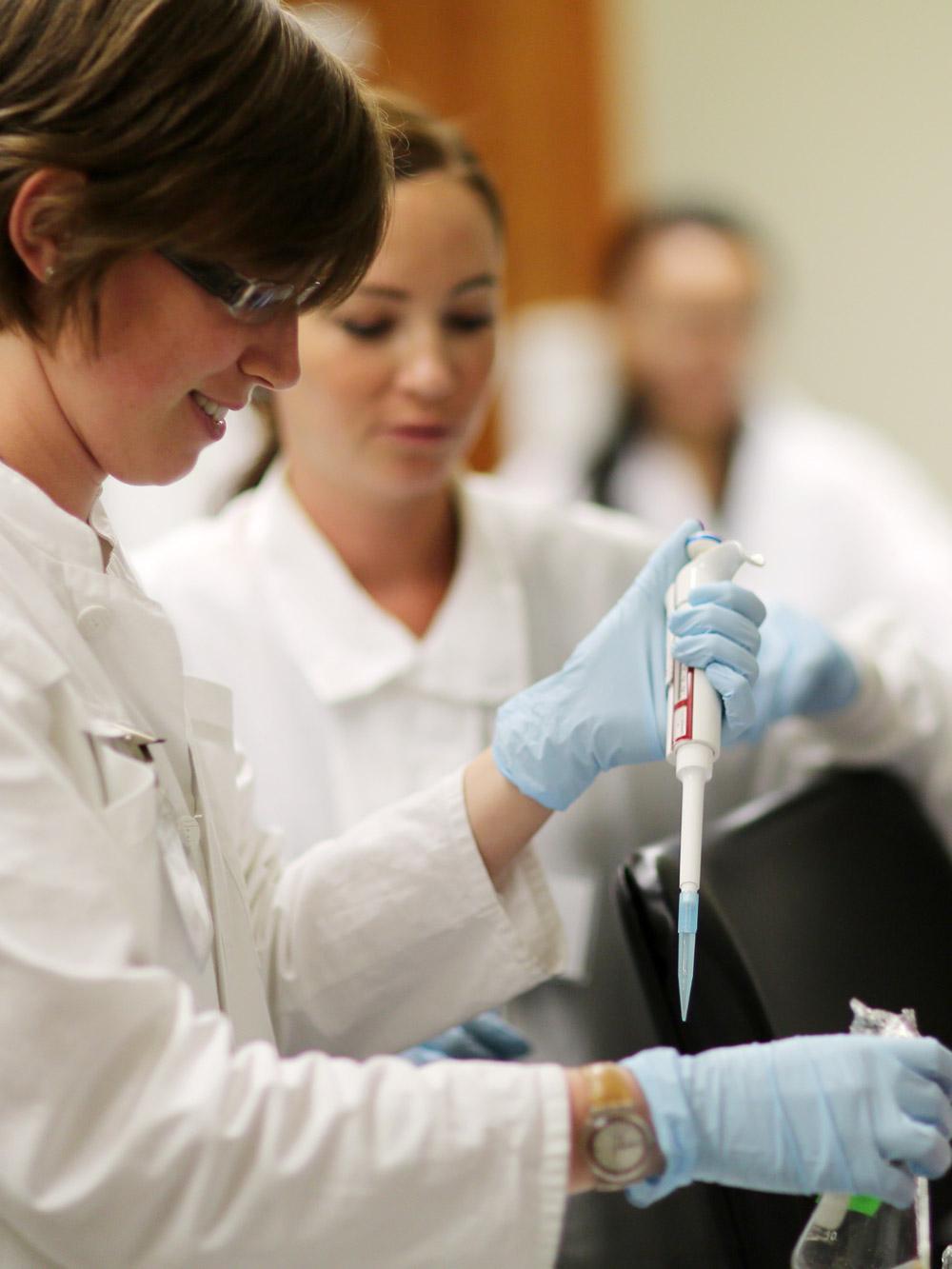 Two students using a pipet during an laboratory exercise.